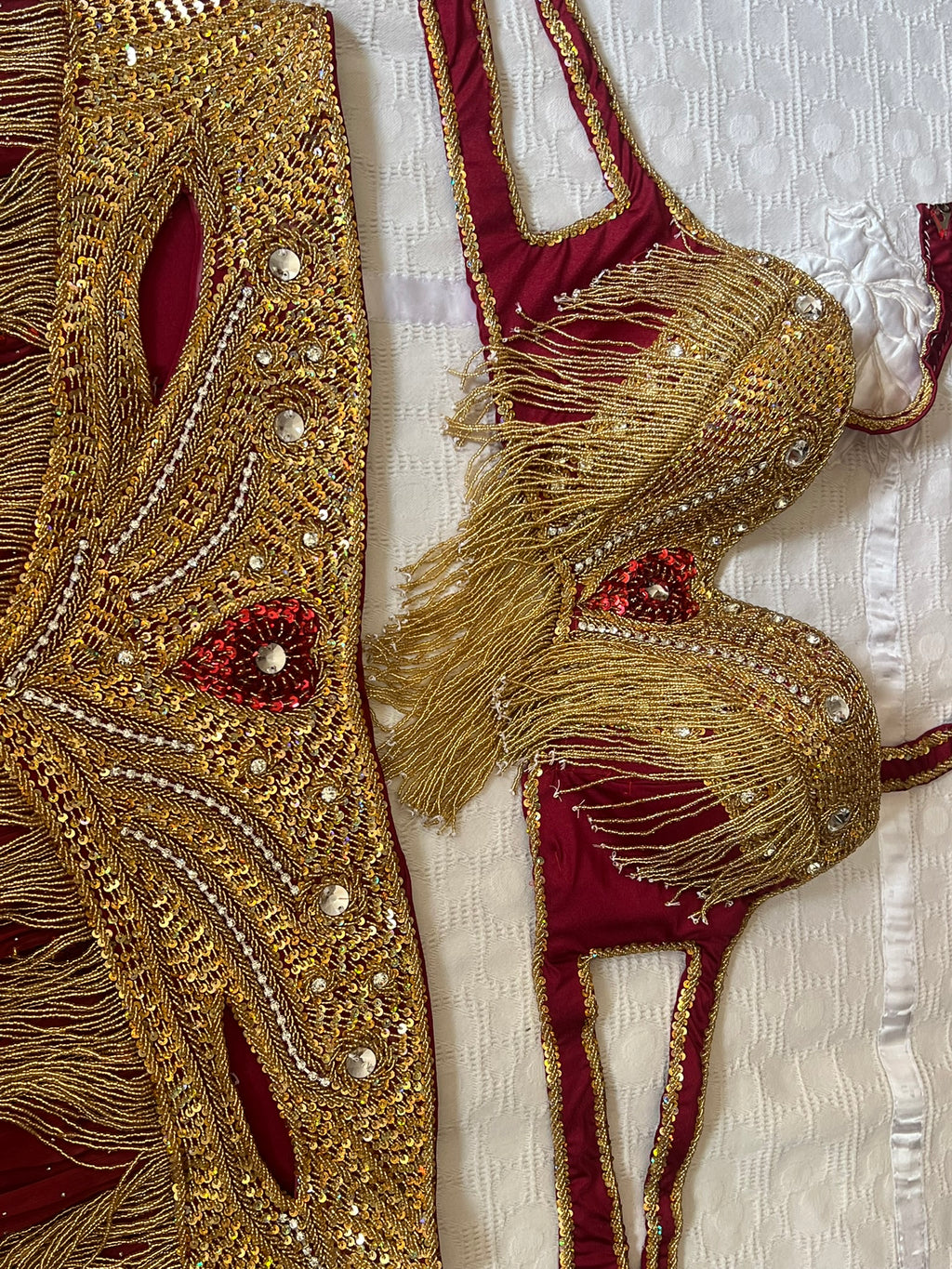 Decorative gold and red garment with intricate patterns on a textured white background