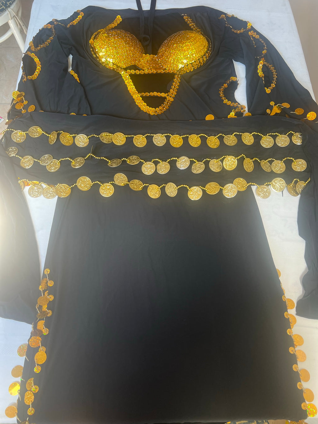 A black belly dance costume with gold and multicolor embroidery, including a bra top adorned with golden circles.