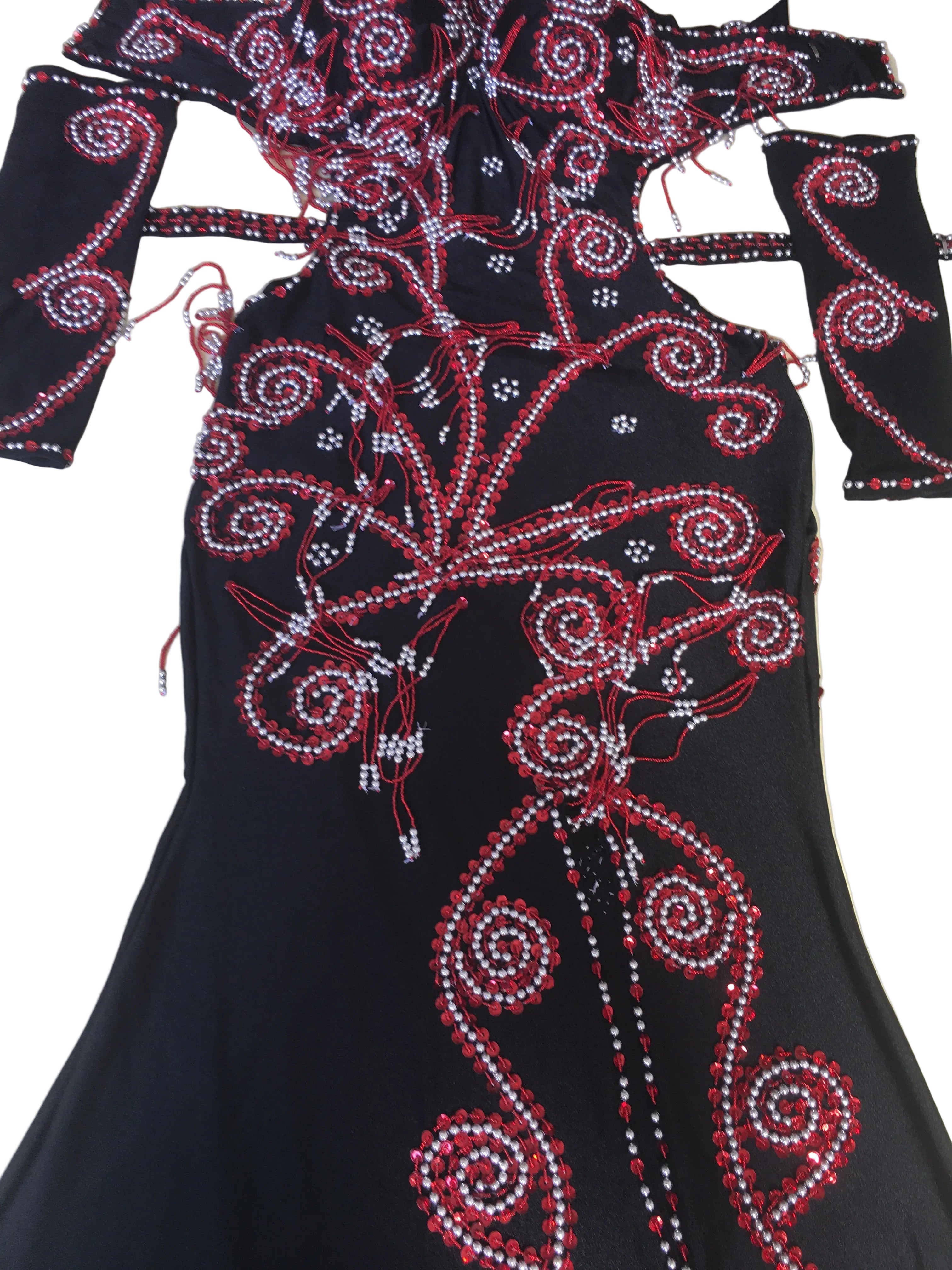A black belly dance costume with handmade embroidered details, including a skirt with front slit and a bra, accompanied by two sleeves and a headband, all adorned with glass beads and sequins.
