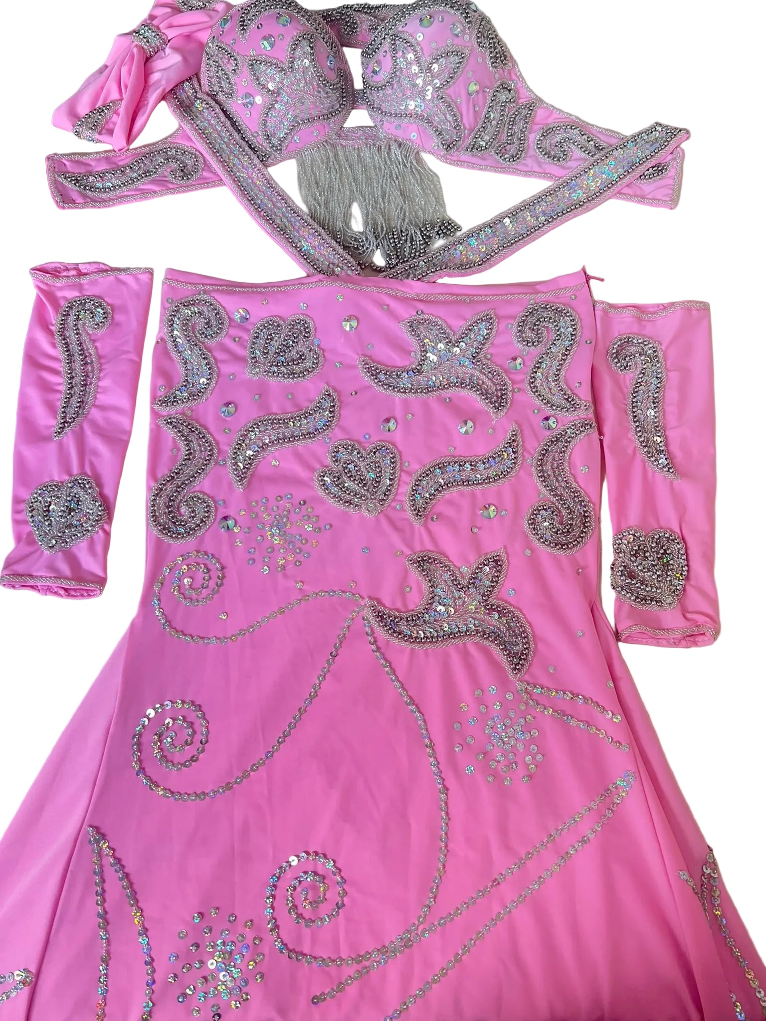 A custom-made pink belly dance costume with intricate hand embroidery, large clear glass stones, glass beads, and sequins, including a headband and a pair of sleeves.
