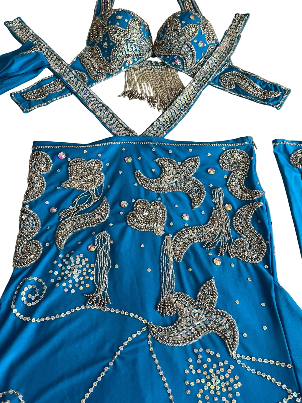 A detailed image of an Egyptian belly dance costume featuring a blue skirt with elaborate silver embroidery, a matching bra, sleeves, and a headband.