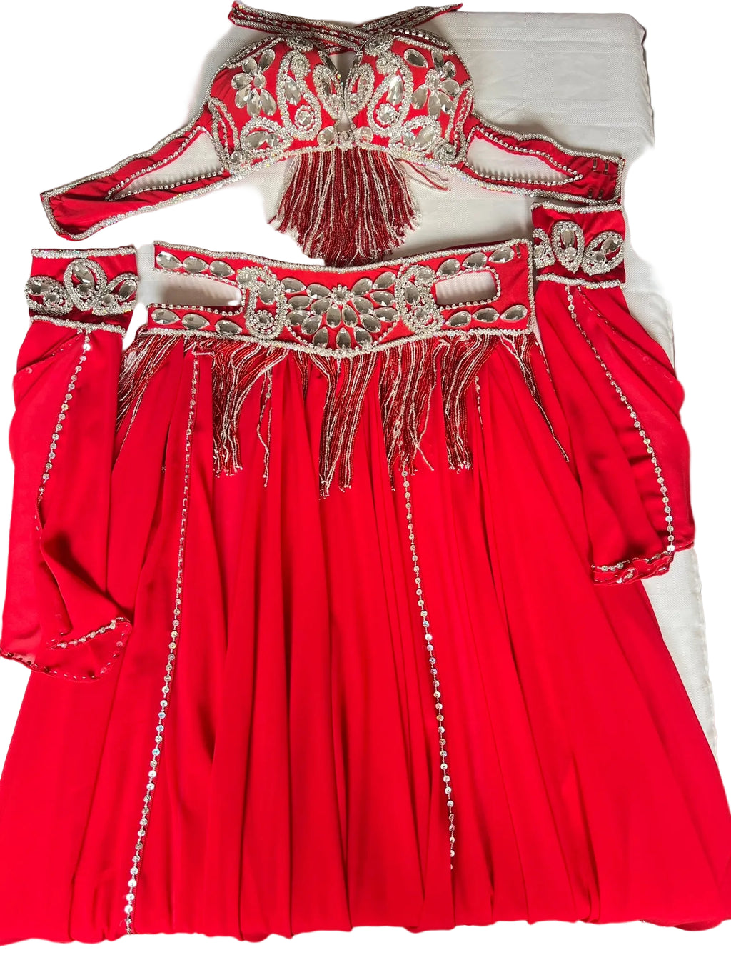 A professional red belly dance costume with a double-layer chiffon skirt, including a bra and a belt with decorations, placed on a white surface.