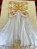 A professional belly dance costume with a white chiffon skirt adorned with gold and multicolored beads, a matching bra, and additional decorations.