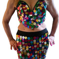 A person wearing a colorful belly dance costume with embroidered details and a sequined top.