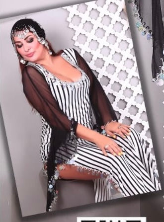 A woman modeling a striped belly dance dress with long sleeves and a hip scarf. The dress features multicolored stripes with embellishments.