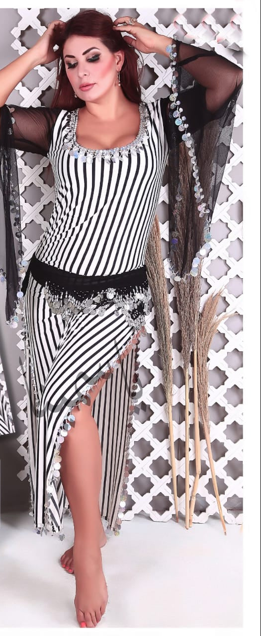 A woman modeling a striped belly dance dress with long sleeves and a hip scarf. The dress features multicolored stripes with embellishments.