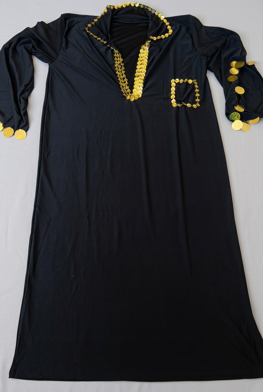 Black Egyptian Saidi galabia laid flat on a beige surface, showing gold-tone sequin edging and split sleeves.
