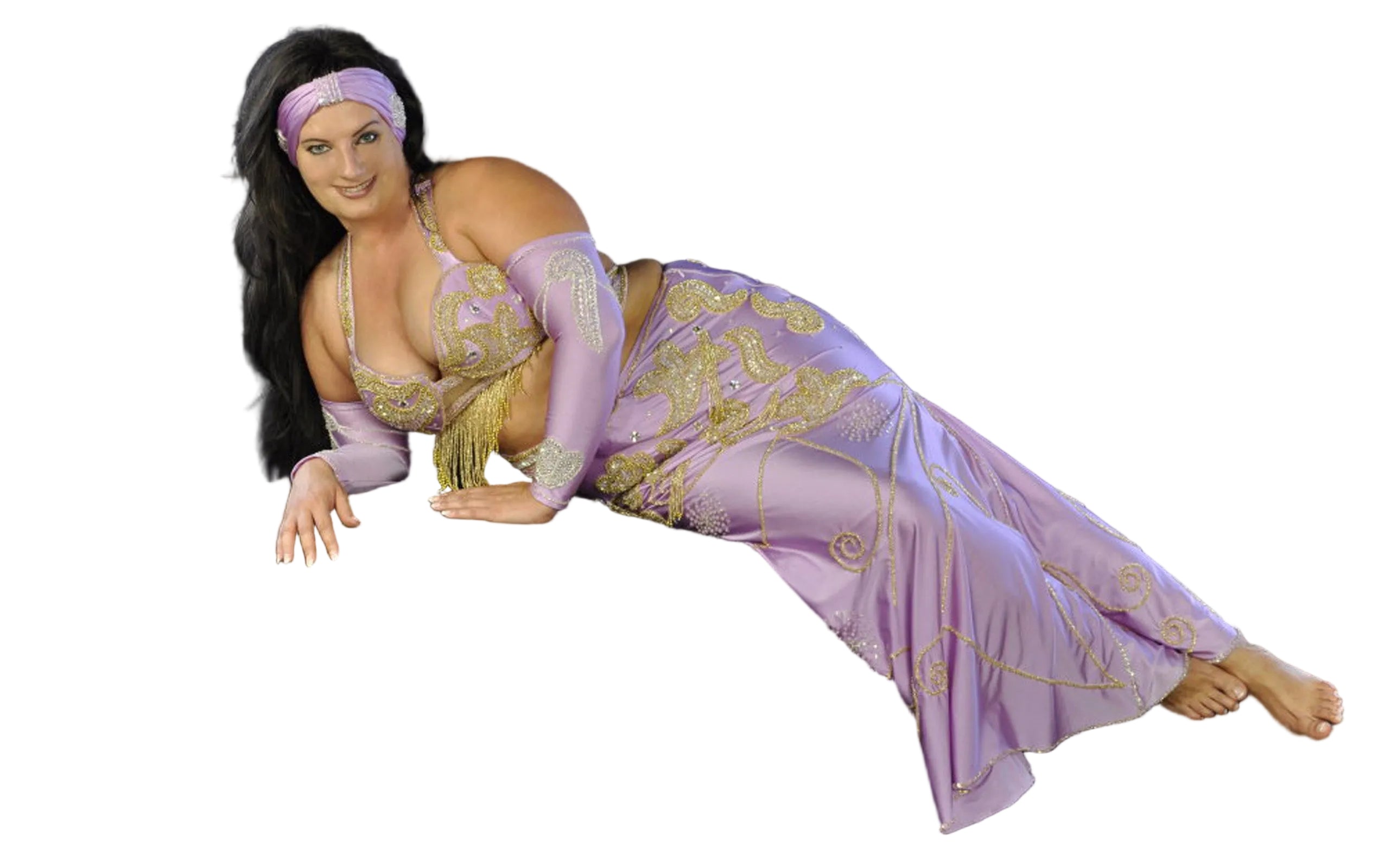 A person posing in a purple belly dance costume with embellishments, including a skirt, bra, sleeves, and a headband.