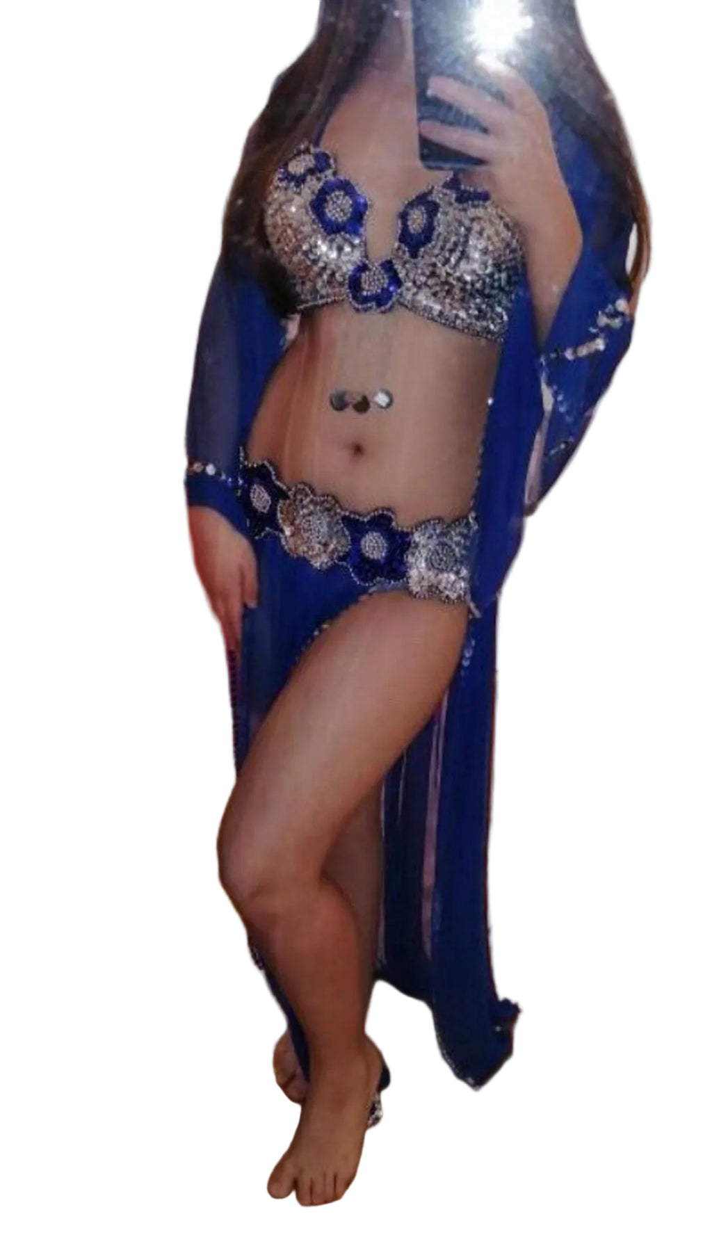 A woman wearing a handmade red belly dance dress with a bra and belt, and a tulle skirt. The image is blurred and has a reflective quality.