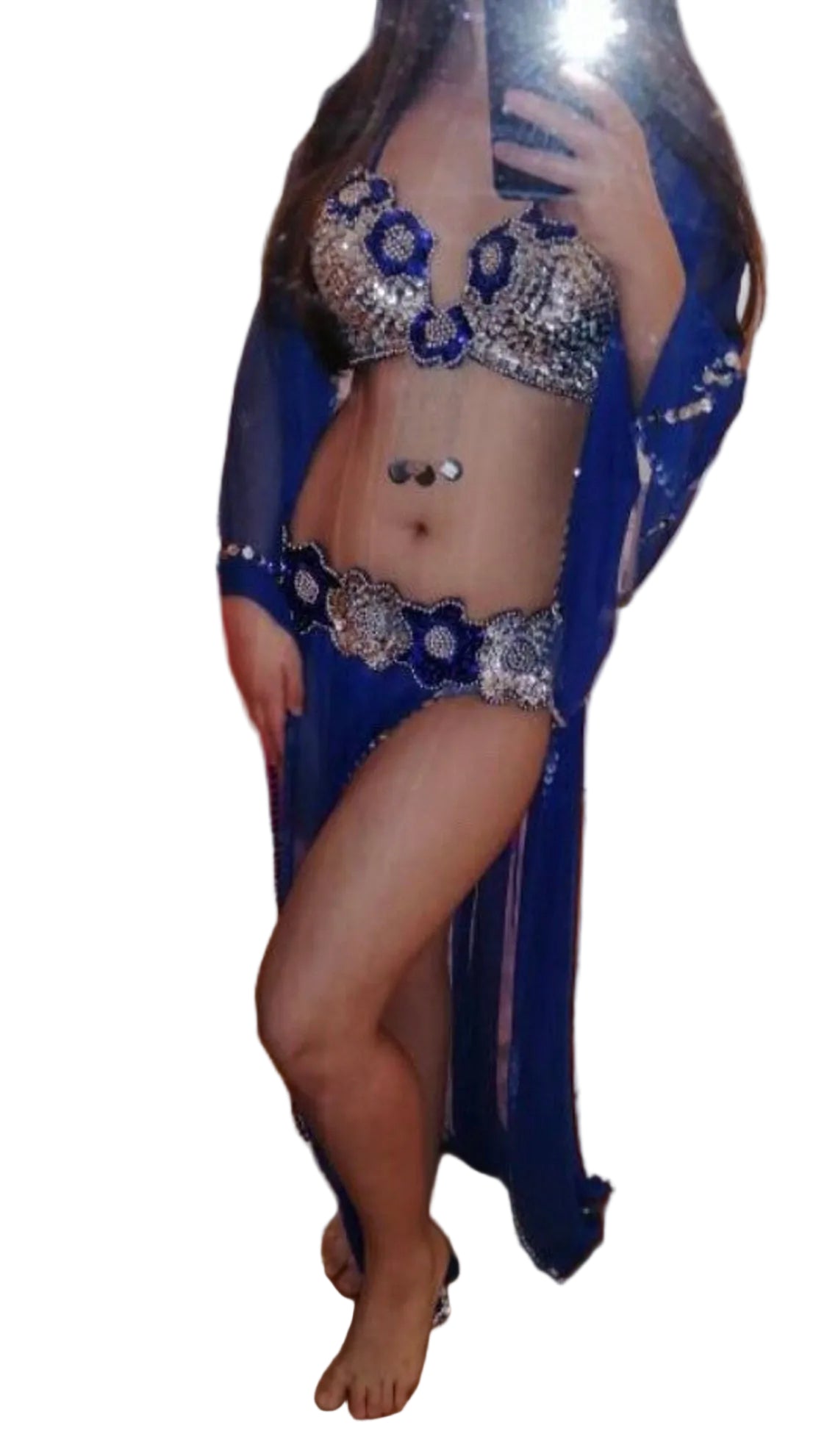 A woman wearing a handmade red belly dance dress with a bra and belt, and a tulle skirt. The image is blurred and has a reflective quality.