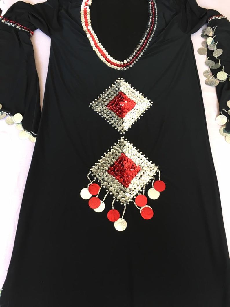A black belly dance dress with red and white geometric embroidery and silver accents, displayed on a mannequin.
