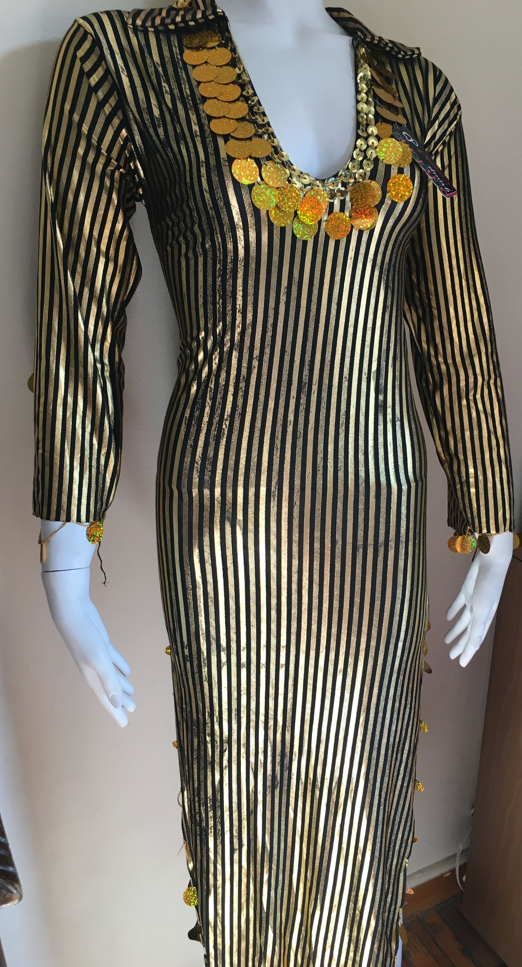 Mannequin wearing a black and gold striped dress with floral embellishments on a plain background
