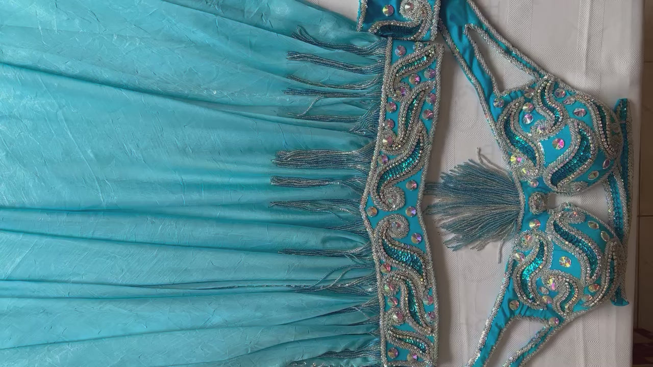 Video showcasing a premium handmade belly dance costume in turquoise fabric, beautifully adorned with silver beads, glass stones, and rhinestones.