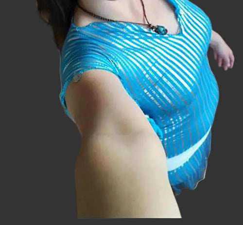 Woman in a blue dress taking a selfie in an indoor setting.